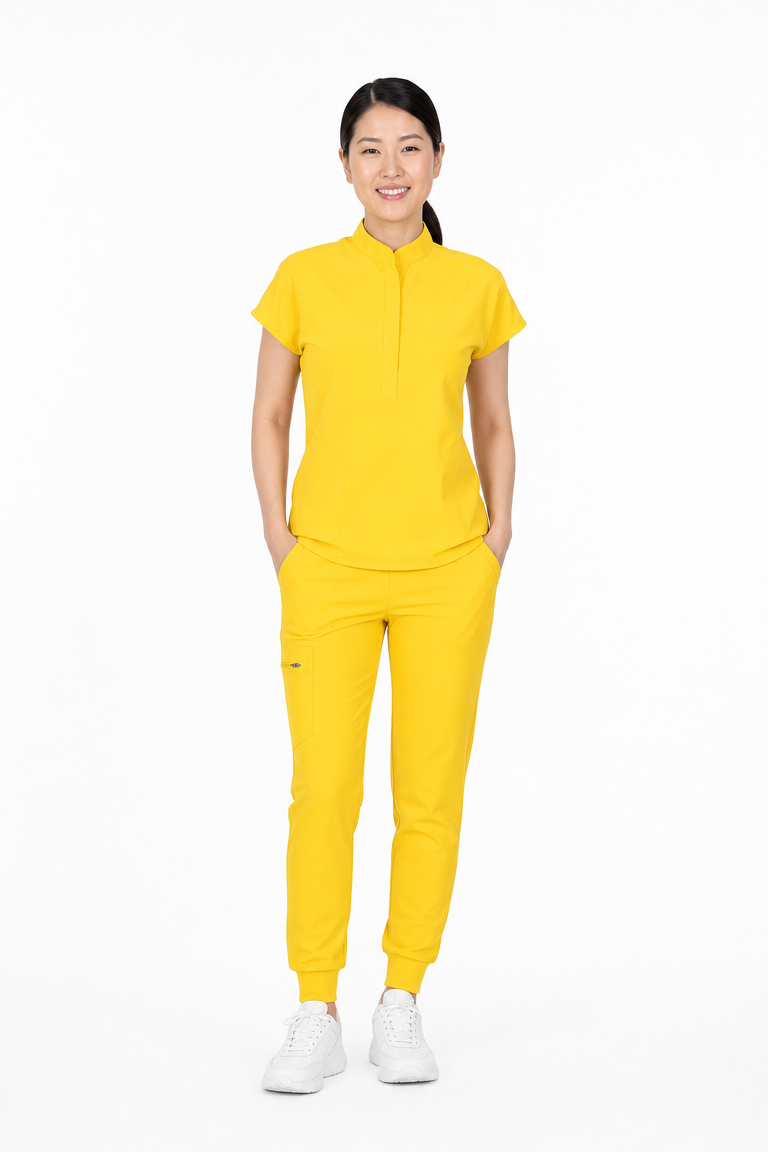 A woman modeling a bright yellow two-piece tracksuit consisting of a short-sleeve mock-neck top and matching jogger pants, paired with white sneakers, against a plain white background.